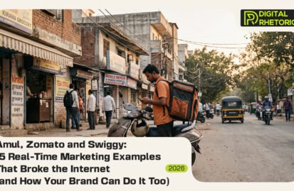A delivery partner in an orange shirt with a backpack standing next to a scooter on a busy Indian street, looking at his smartphone.